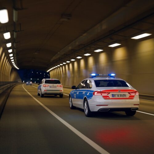 Polizeifahrzeug verfolgt Pkw in einem beleuchteten deutschen Tunnel bei Nacht.